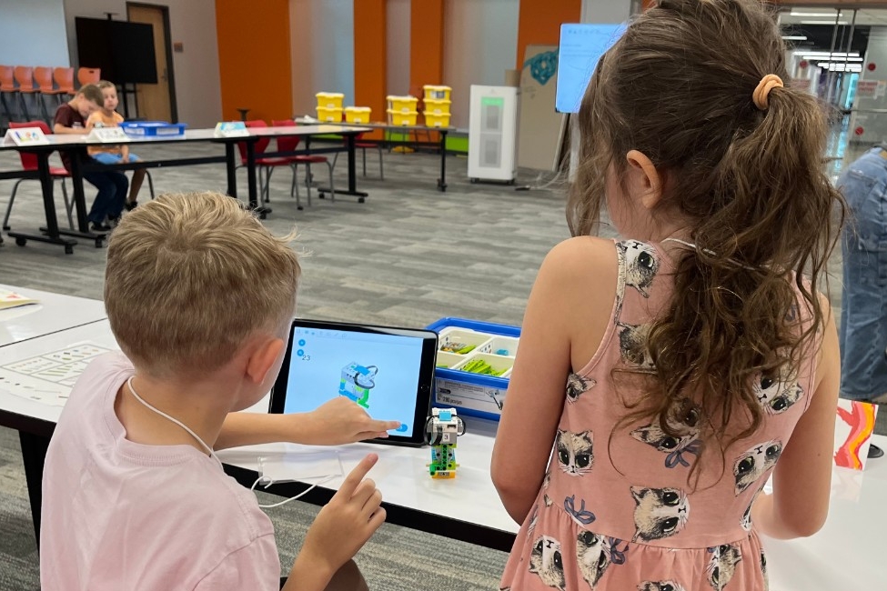 Young kids using elementary programming software to build and code a moving LEGO robot