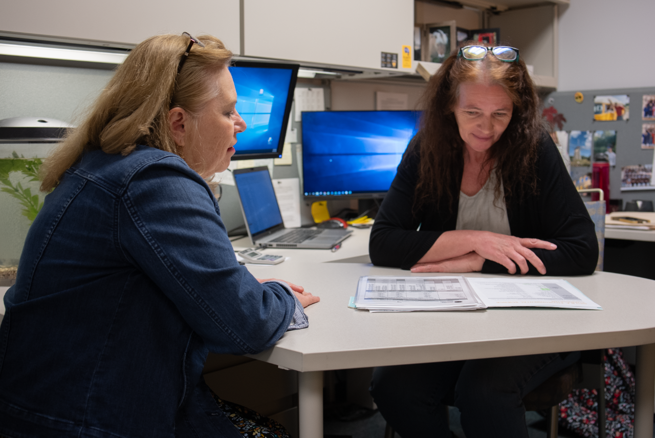 A student meets with her academic advisor in an office.